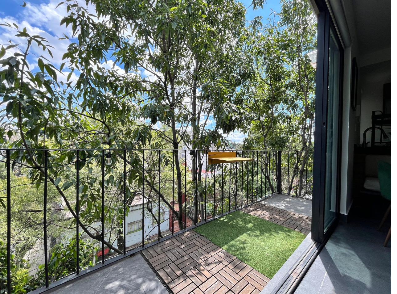 L-balcony ringed by mature tree canopy — leafy outlook, dappled afternoon light