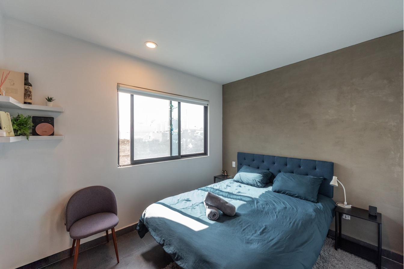 Second bedroom with concrete-finish accent wall and dual window