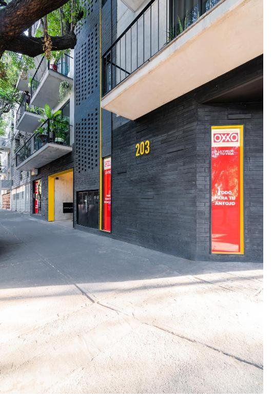 Corner exterior of Tonalá 203 — dark brick façade, address numerals, residential balconies above